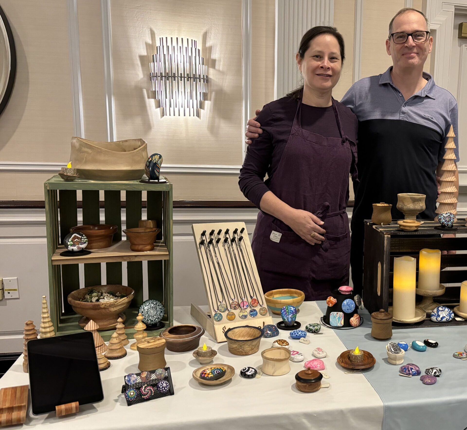 A man and woman stand beside a table displaying an assortment of items, engaged in conversation